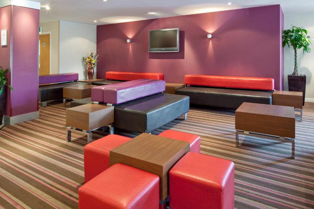 浦耳快捷假日普尔酒店的一间配备有色彩缤纷家具和电视的等候室