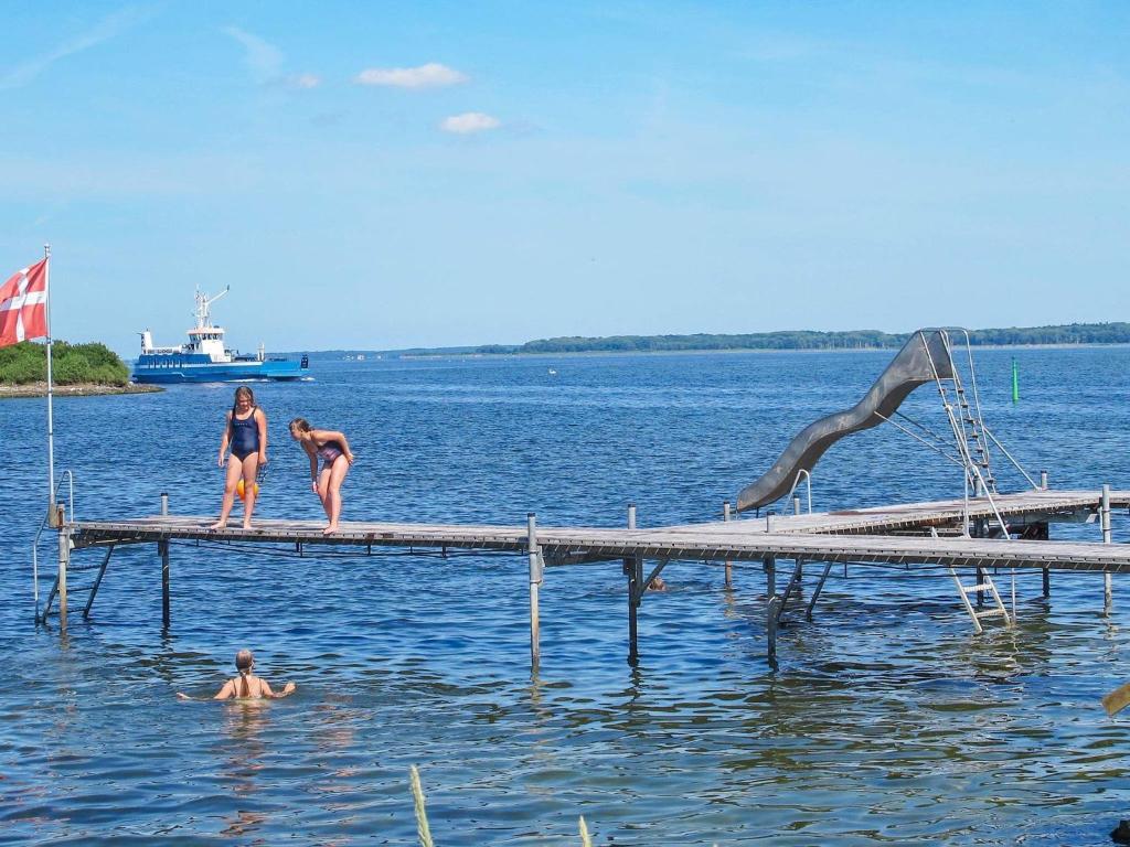 班霍尔姆4 person holiday home in Bandholm的三个女人站在水面上的码头上