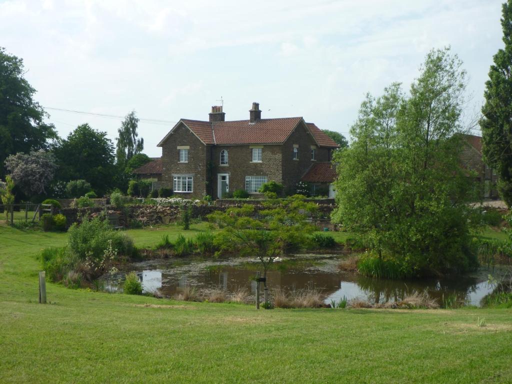 Terrington霍尔农场住宿加早餐旅馆的前面有池塘的房子