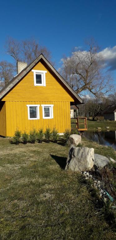 奥泰佩Hommik House的一座黄色的房子,在一座有岩石的院子内