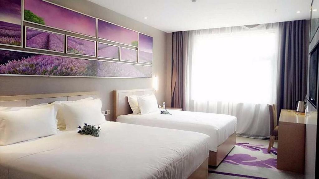 银川麗枫酒店·银川火车站万达店的酒店客房设有两张床,墙上挂有绘画作品