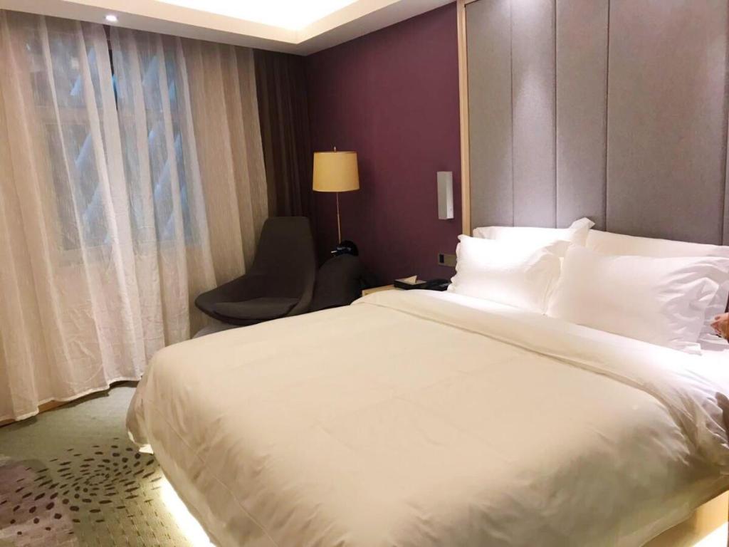 吐鲁番麗枫酒店·吐鲁番大十字店的卧室配有一张白色大床和一把椅子
