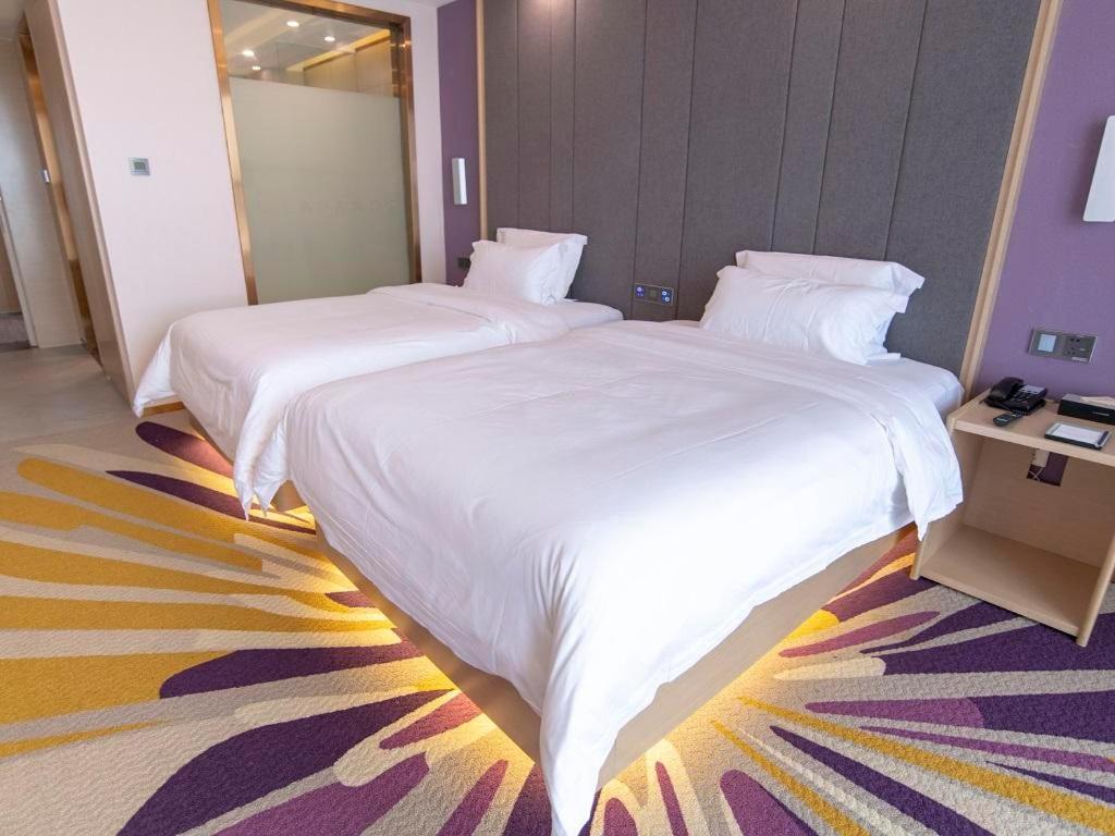巴中麗枫酒店·巴中财富中心店的配有白色床单的酒店客房内的两张床