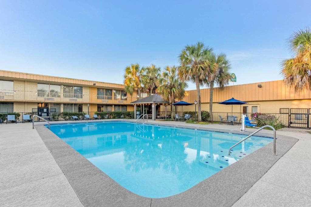 斯莱德尔Quality Inn Slidell I-10的棕榈树建筑前的大型游泳池