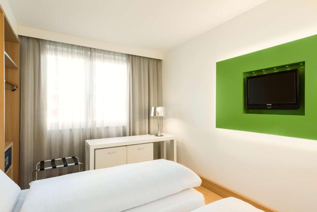 柏林NH酒店波茨坦广场店的一间设有床铺和墙上电视的客房