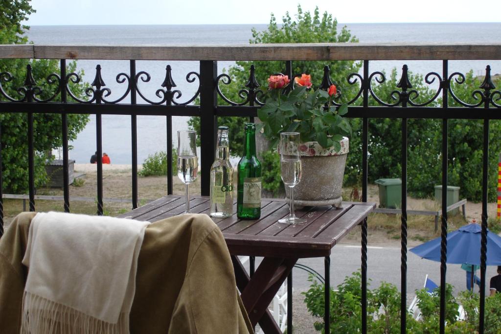 奇维克STF Kivikstrand Badhotell的木桌,带酒杯和鲜花的围栏