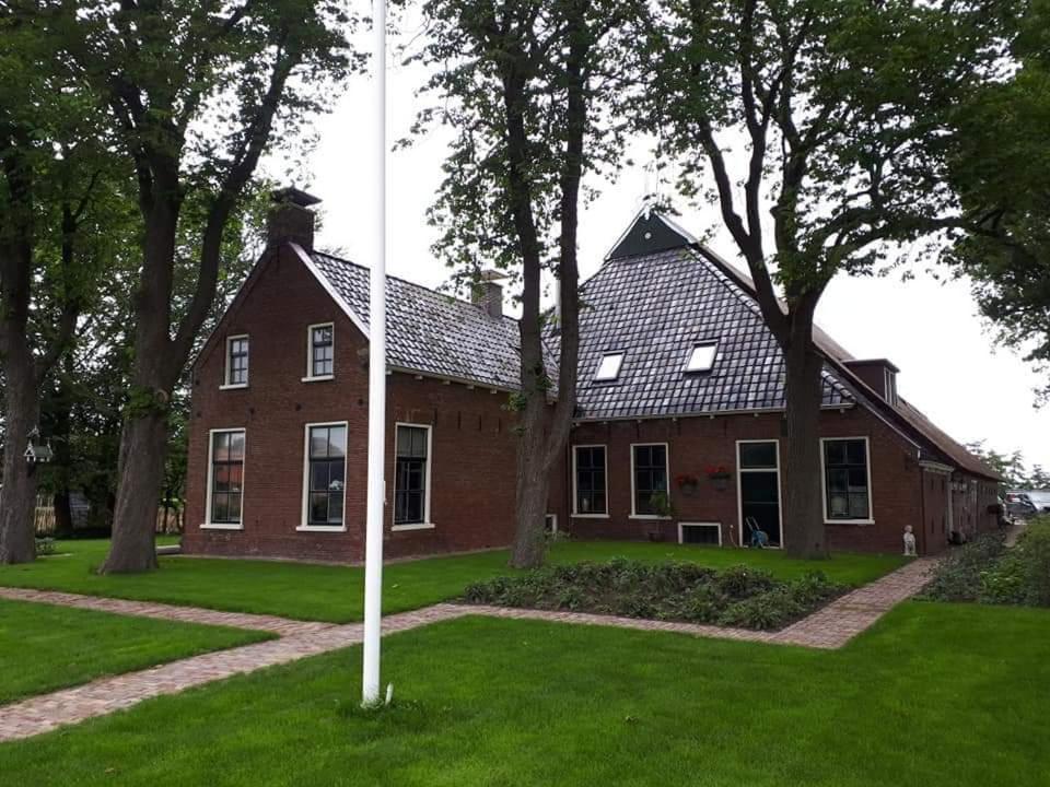 OpeindeB&B De Herenboer的草上有一根杆的红砖房子