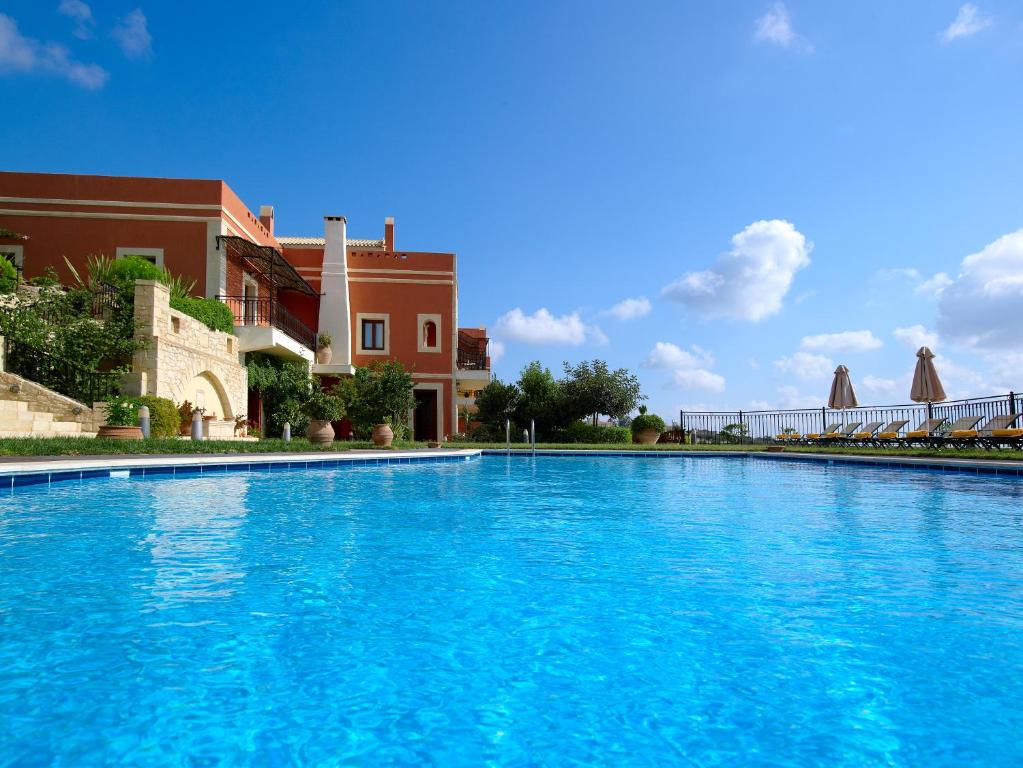 阿卡尼斯卡塔拉加里乡村套房酒店的一座大型蓝色游泳池,位于大楼旁边