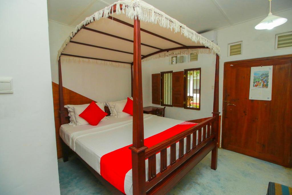 马特勒Hotel Nawathana的一间卧室配有一张带红色枕头的木制天蓬床