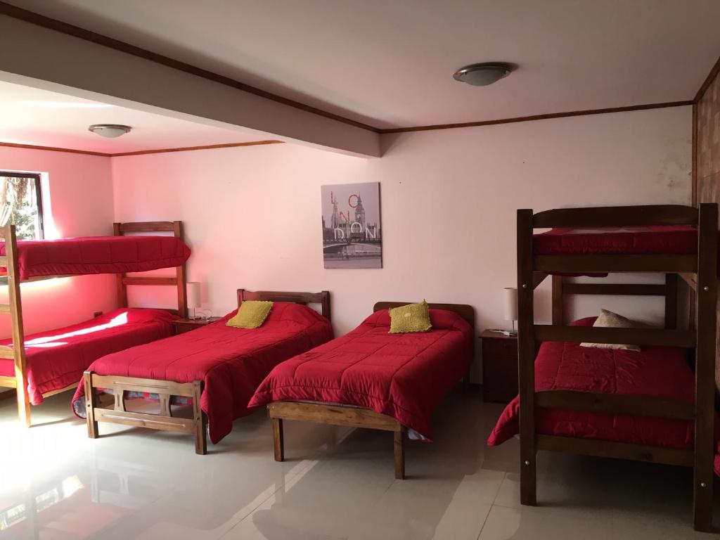 De CauquenesHOSTAL CAUQUENES的红色床单的客房内的两张床