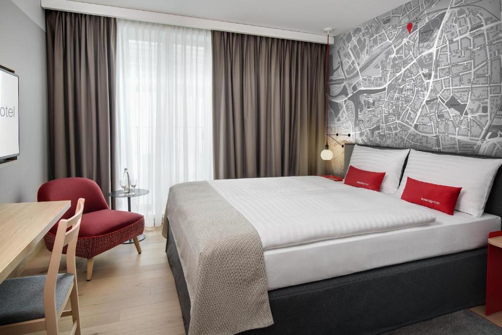 希尔德斯海姆IntercityHotel Hildesheim的酒店客房,配有一张床和一张红色椅子