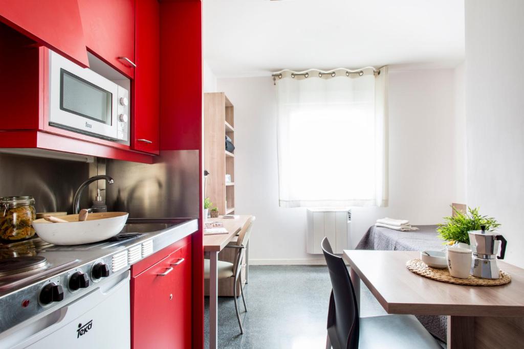 特拉萨Alojamientos Universitarios Hipatia的一间带红色橱柜和餐桌的厨房