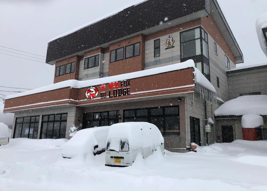 妙高Red Fox Lodge Myoko的建筑前的积雪覆盖的商店