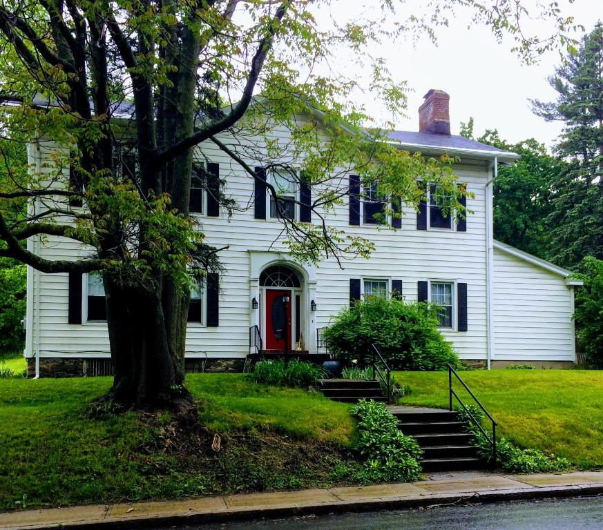 特洛伊Gardner Farm Inn的一间白色的房子,有红门和一棵树
