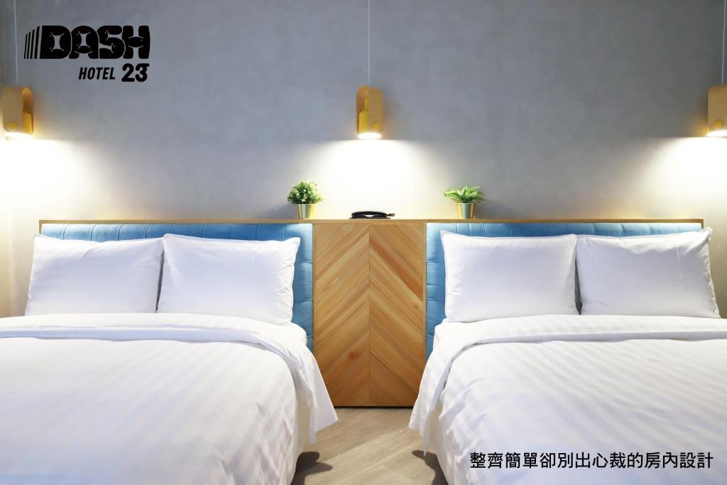台南达煦23旅店的客房内的两张床和白色床单