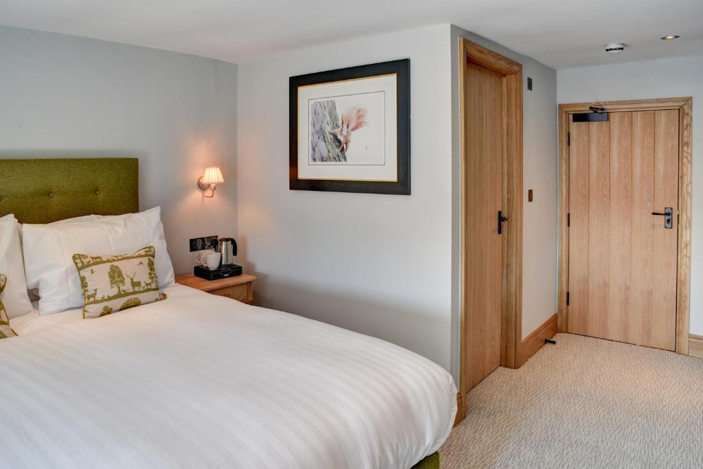 牛顿阿伯特Barn Owl Inn的卧室配有白色的床和木门