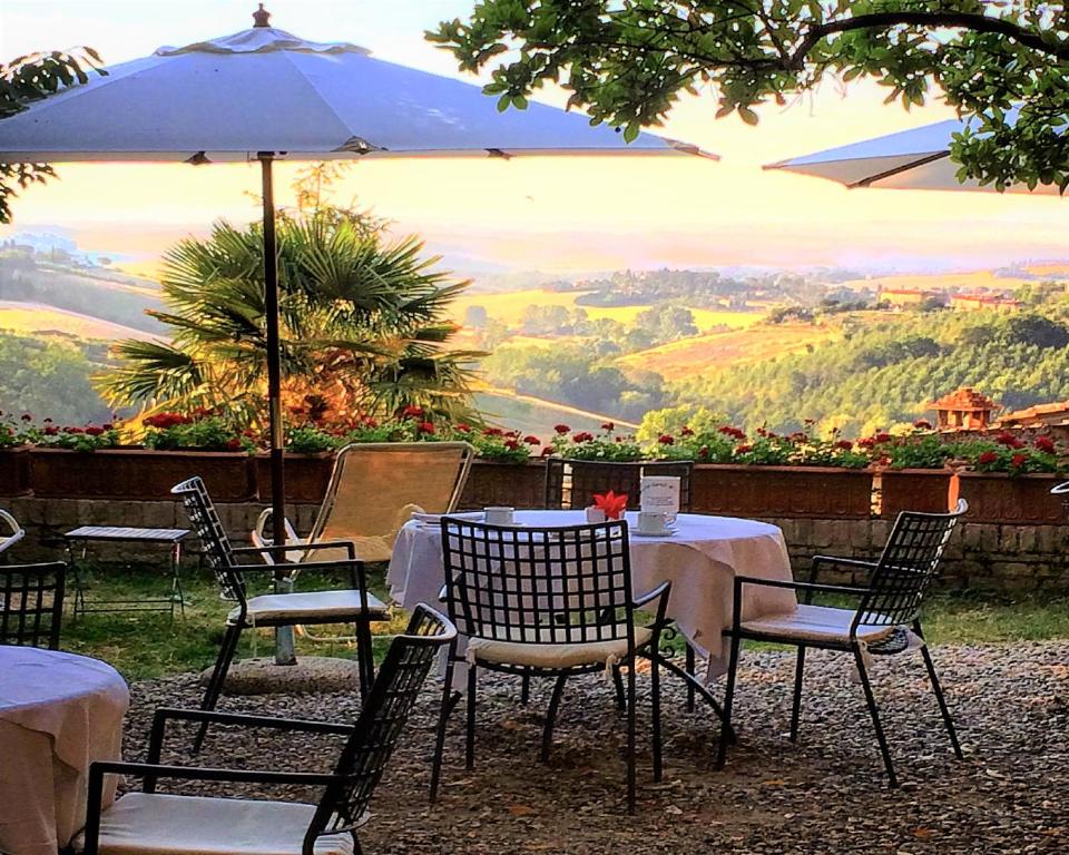 锡耶纳圣卡塔林纳酒店的一张桌子、椅子和一把伞,享有美景