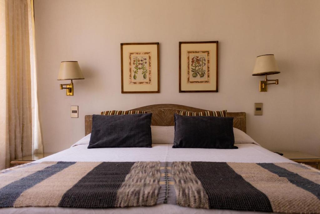 圣地亚哥Alessandria Apart - Coronel Pereira的卧室配有一张床,墙上挂着两盏灯