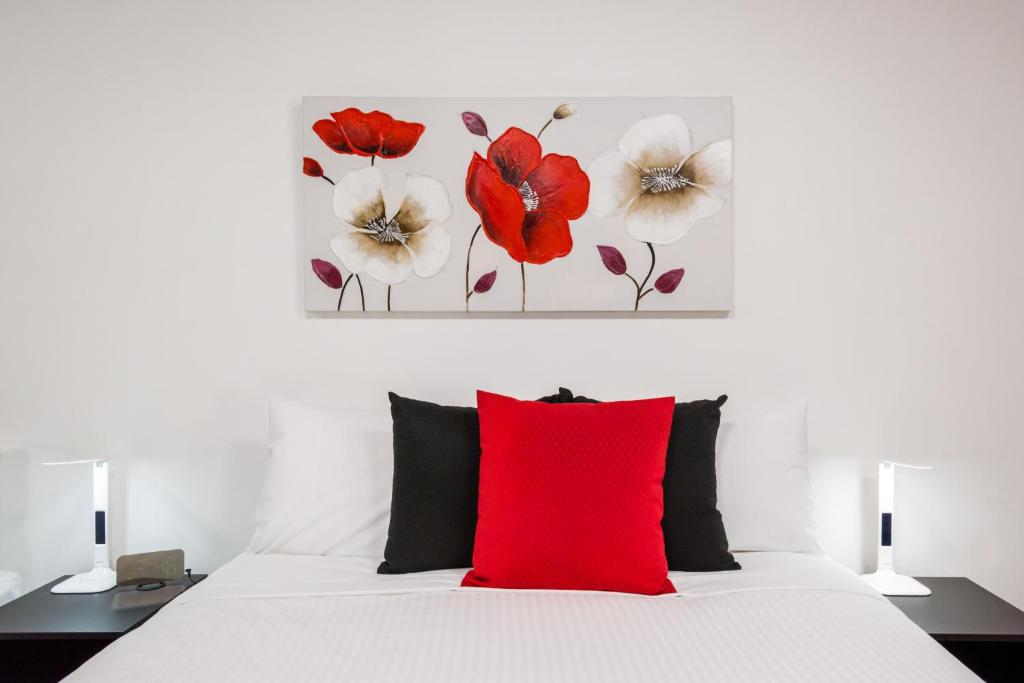 尤罗亚尤罗阿汽车旅馆的卧室配有白色的床和红色枕头