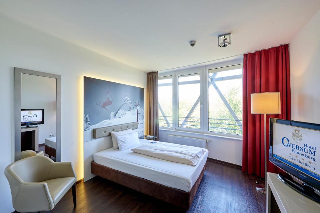 温特贝格Hotel Oversum Winterberg Ski- und Vital Resort的一间卧室配有一张床、一台电视和一把椅子