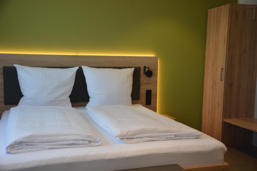 Klein-WinternheimWeingut Bugner Meizelhof的一张带两个白色枕头和绿色墙壁的床