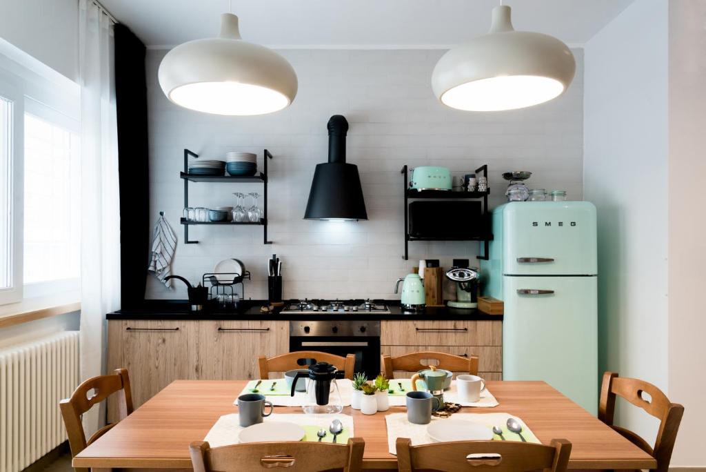 泰拉奇纳BOTTASSO17 Guest House a due passi dal mare的厨房配有木桌、椅子和冰箱