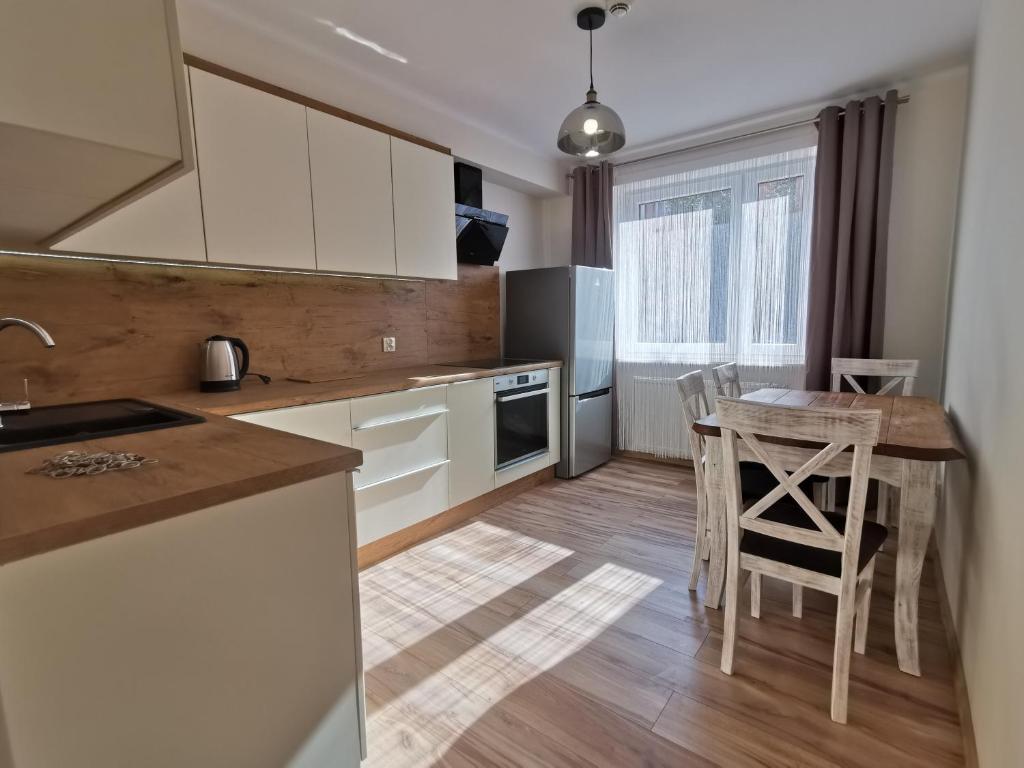 科宁Apartament KAKADU的厨房配有白色橱柜和桌椅