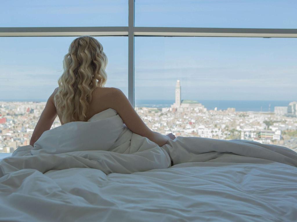 卡萨布兰卡卡萨布兰卡布兰奇索菲特大酒店的坐在床上看着窗外的女人