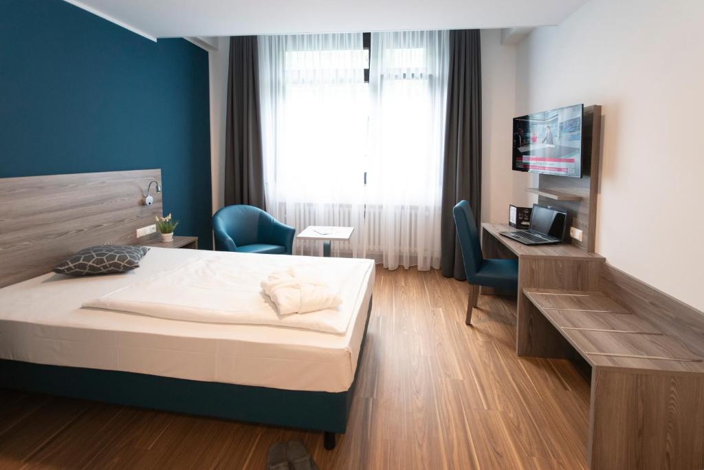 埃森New Work Hotel Essen的一间卧室配有一张床、一张书桌和一台电视