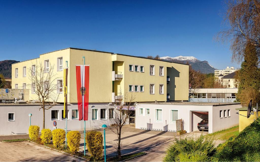 菲拉赫居肯迪菲拉赫家庭酒店的一座黄色的大建筑,有白色的建筑和山脉