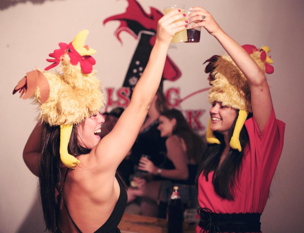拉戈斯Rising Cock Party Hostel的两个女人在聚会上喝杯啤酒