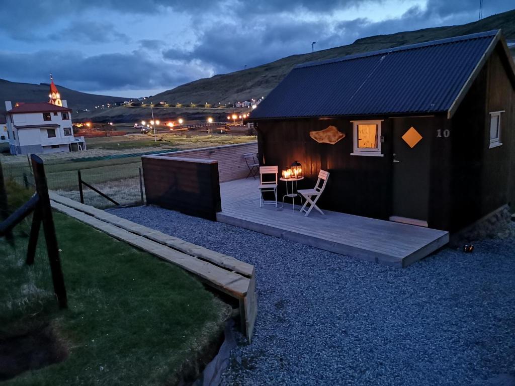 SandavágurHjallurin的小屋设有木制甲板和桌椅