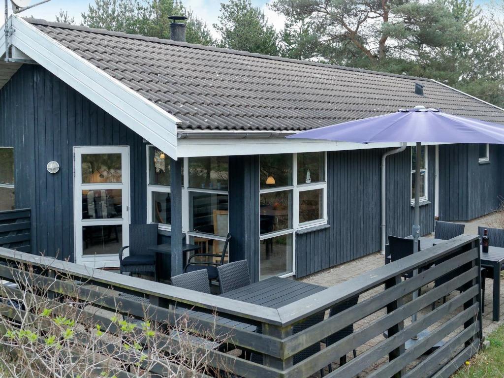 图鲁普斯特兰德6 person holiday home in Fjerritslev的蓝色的房子,带雨伞的甲板