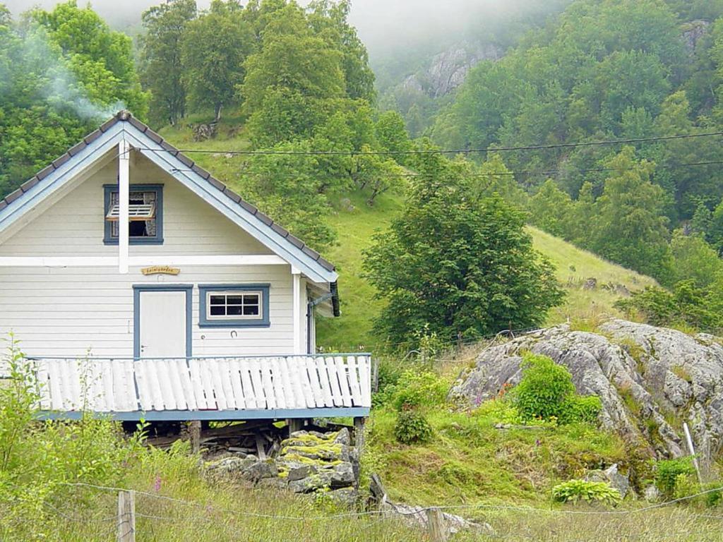 KyrpingThree-Bedroom Holiday home in Åkra的一座小白房子,位于山丘上,树木繁茂