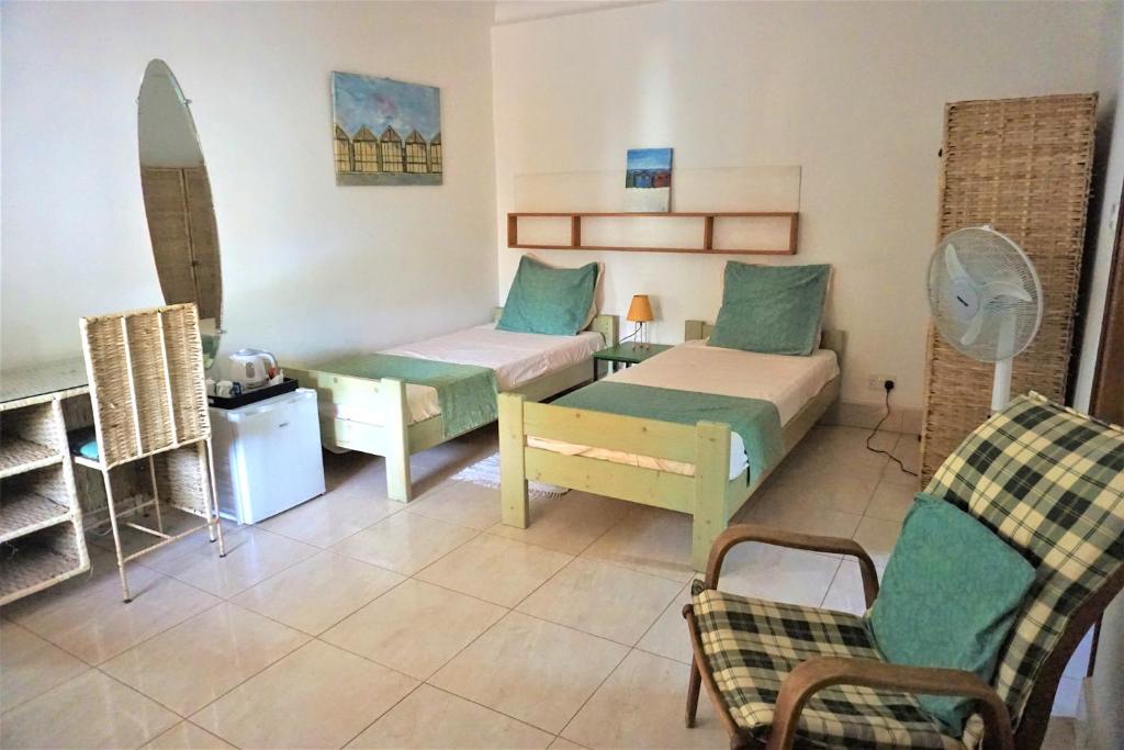 BijiloB & B Villa Calliandra的一间设有两张床、一张沙发和一把椅子的房间