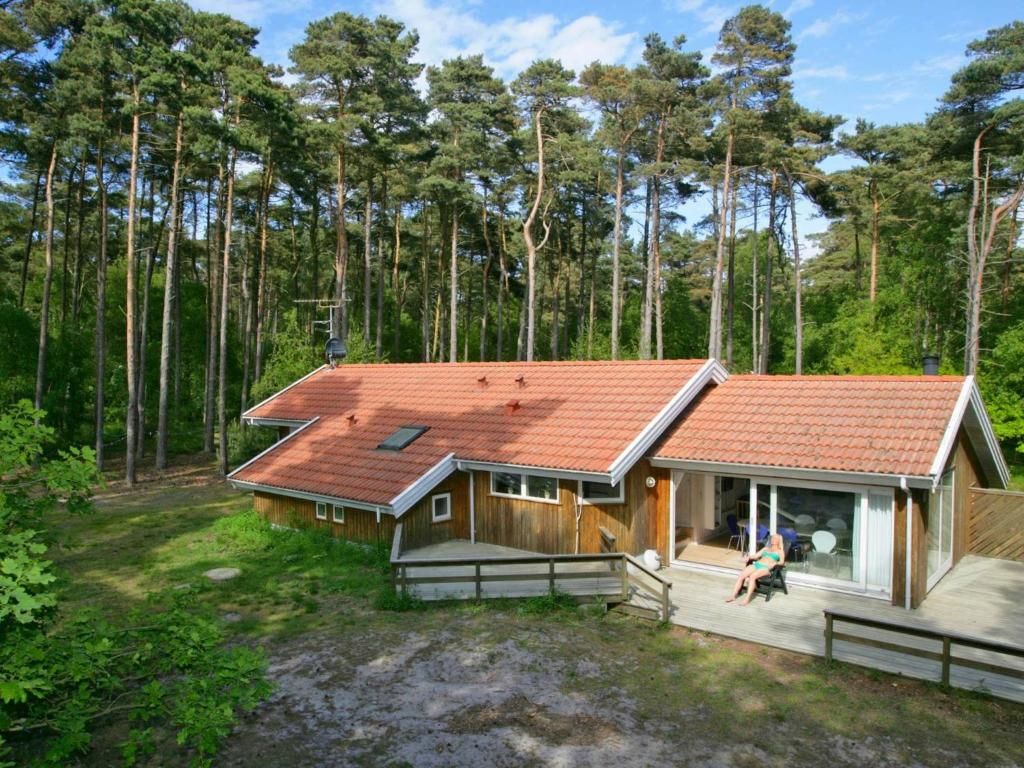 斯皮兹嘉德Four-Bedroom Holiday home in Nexø 14的树林里一座带橙色屋顶的房子