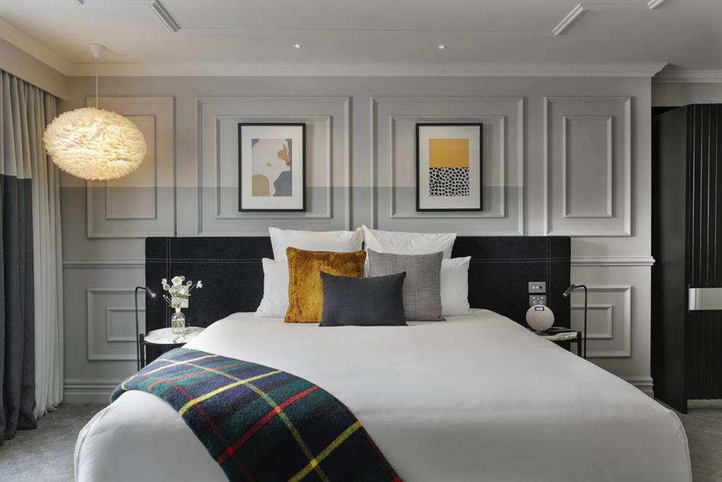 但尼丁Fable Dunedin的卧室配有一张白色大床和吊灯。