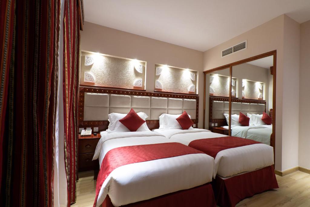 多哈Al Liwan Suites Rawdat Al Khail的酒店客房,设有两张床和镜子
