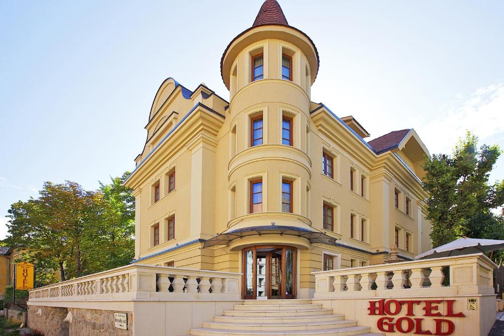 布达佩斯布达佩斯黄金酒店的一座黄色的大建筑,顶部设有钟楼