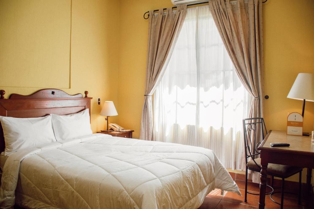 圣萨尔瓦多维拉特拉酒店的一间卧室配有一张床、一个窗口和一张书桌