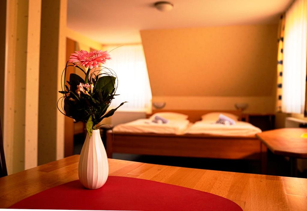 霍恩-巴特迈恩贝格Havergoh Wander- & Fahrrad-Hotel的客房内的白色花瓶,桌子上摆放着鲜花