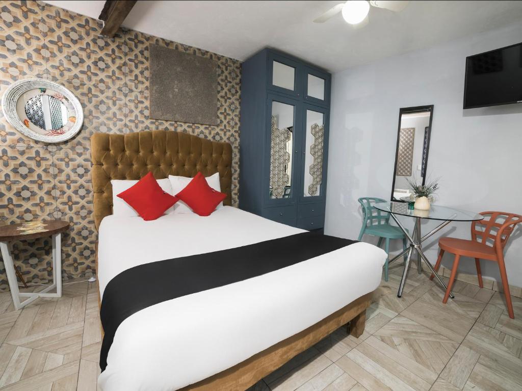 墨西哥城Coyotito Beds Coyoacan, suites a tu alcance!!!的一间卧室配有一张带红色枕头的床和一张桌子