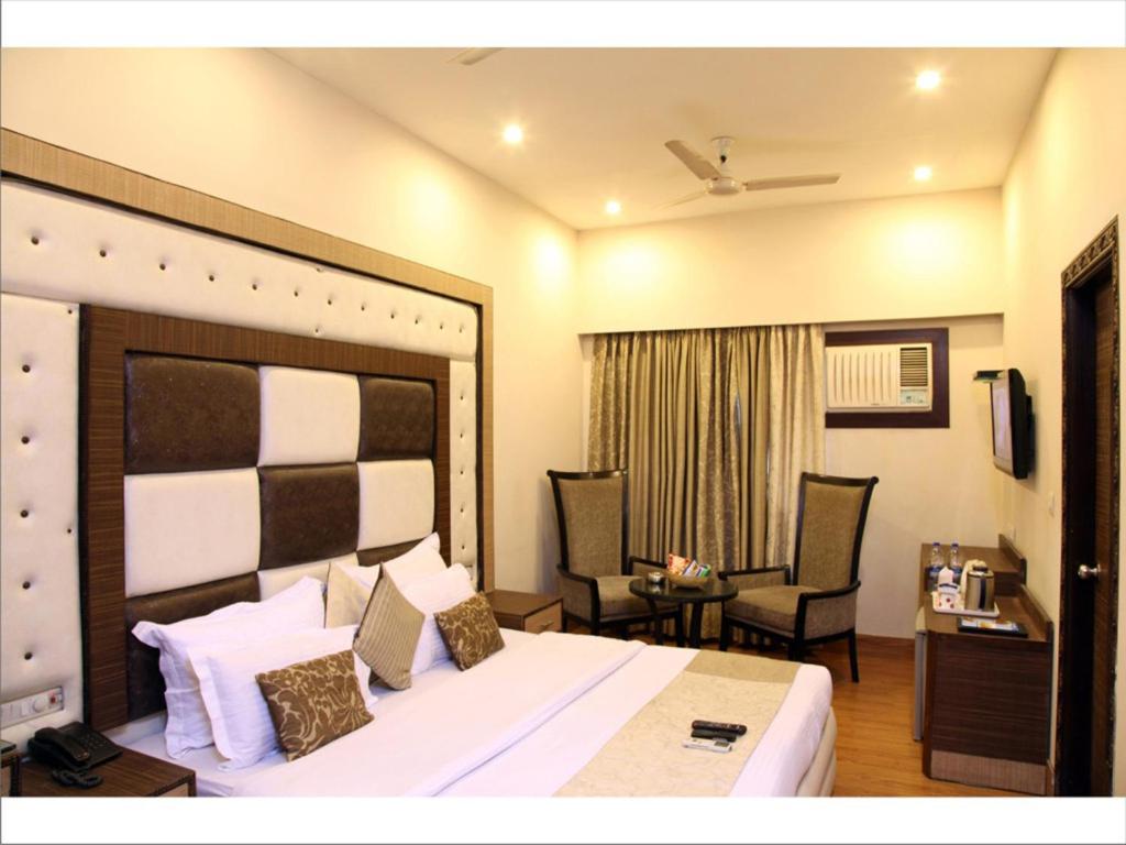 新德里鲁帕马酒店的酒店客房带一张大床和两张椅子