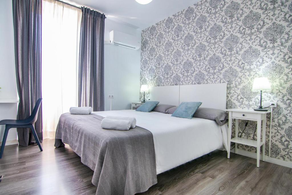 瓦伦西亚卡蒂亚环保住宿加早餐旅馆的卧室配有一张白色大床和一把椅子