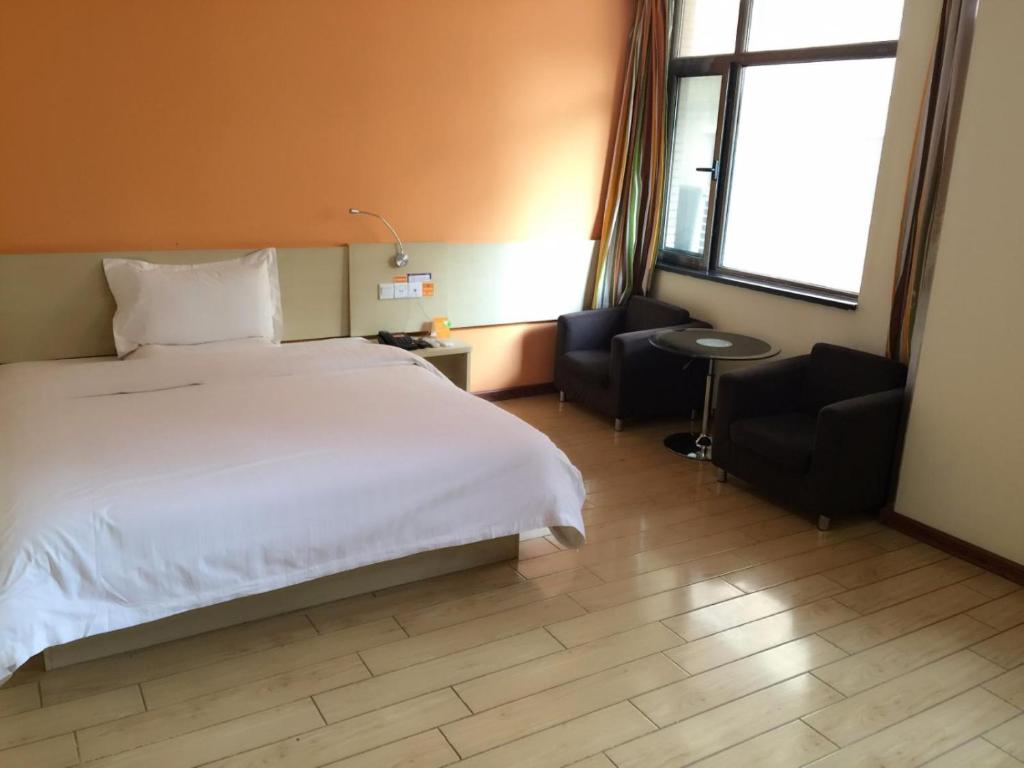 Taoyang7天酒店·临洮城市金街店的卧室配有一张白色大床和两把椅子