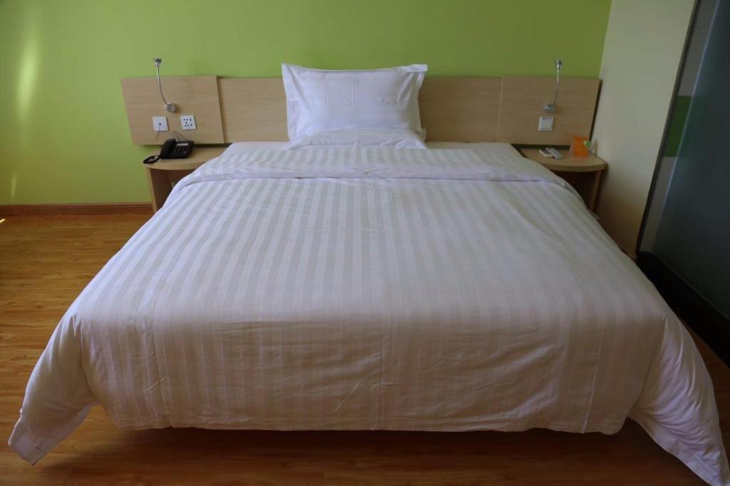 哈密7天酒店·哈密宝丰市场店的一张大白色的床,位于带两张桌子的房间