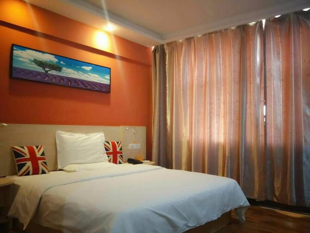 巴彦淖尔7天酒店·临河火车站店的一间卧室配有一张白色的床和橙色的墙壁