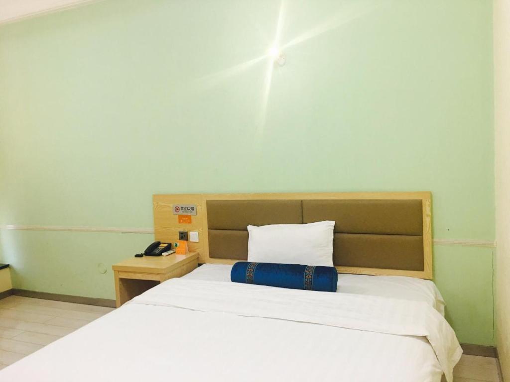 哈尔滨7天酒店·哈尔滨火车站南广场店的卧室配有白色床和蓝色枕头