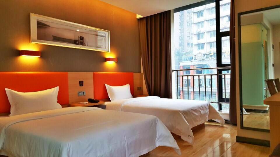 涪陵7天优品·重庆涪陵滨江大道店的酒店客房设有两张床和大窗户。