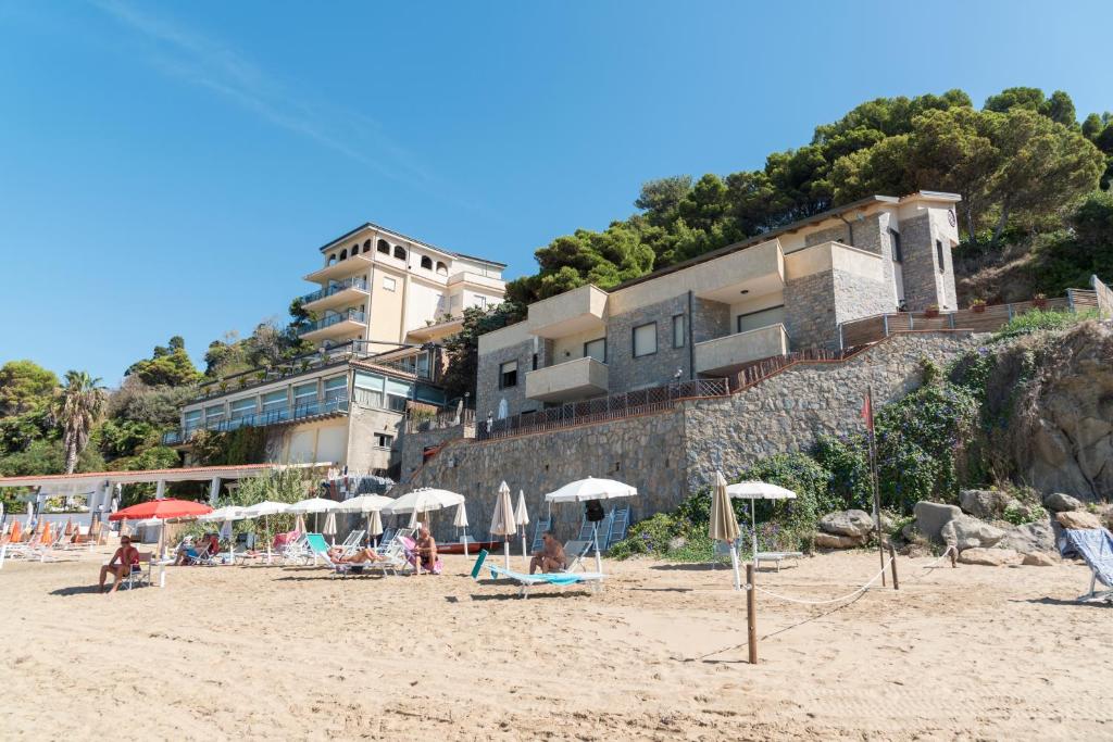 圣塔马里亚迪卡斯特Residenza Fontanelle-Beach Resort的沙滩上,有遮阳伞,有人坐在沙滩上